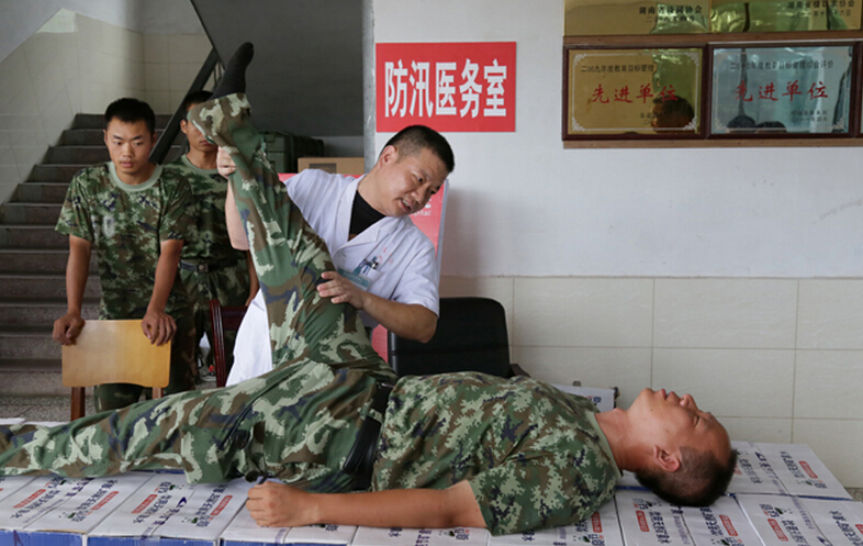 圖為醫(yī)療隊醫(yī)生在為8730部隊武警抗洪部隊官兵進行中醫(yī)正骨治療。